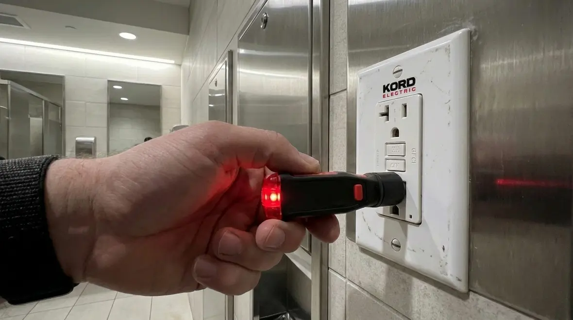 Technician testing GFCI outlets in commercial bathroom
