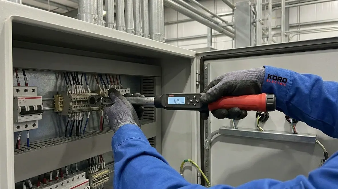 Electrical technician inspecting commercial panels to prevent downtime