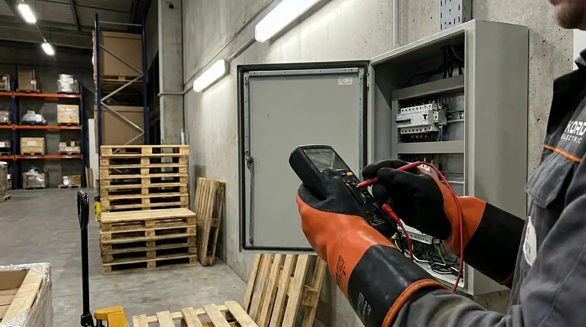 Electrician completing an Electrical Safety Audit Checklist in a commercial electrical room