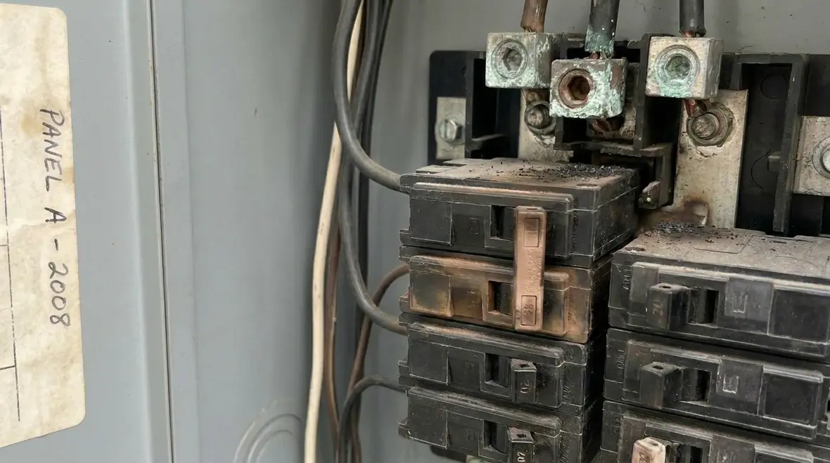 Technician inspecting connections and breakers inside a commercial electrical panel
