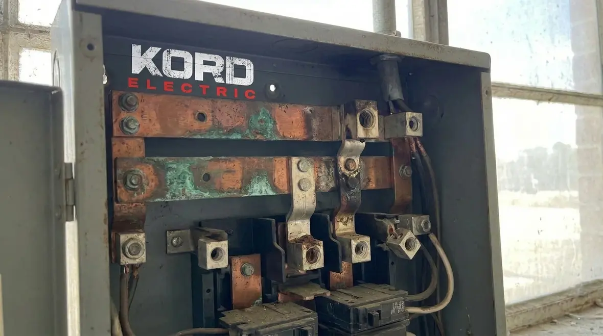 Technician reviewing commercial electrical service capacity in a mechanical room