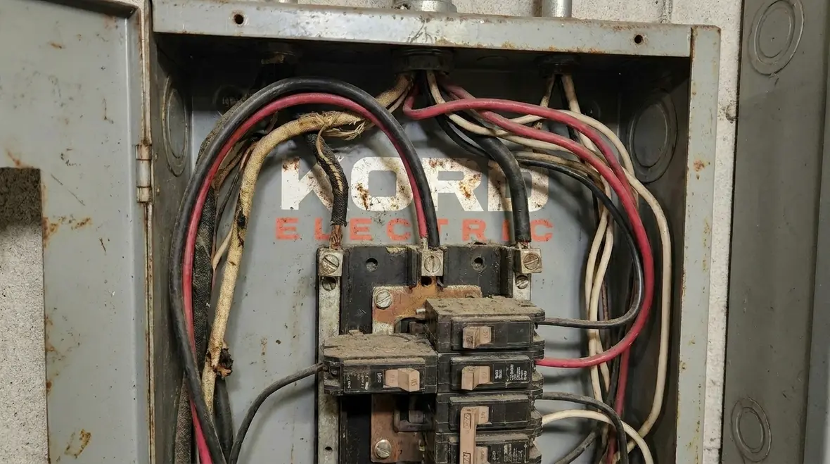 Electrician inspecting commercial electrical panel before lighting retrofit