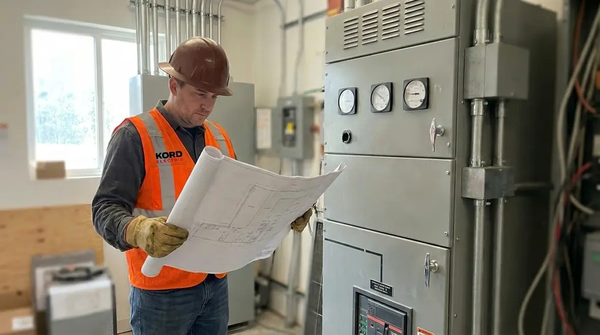 Technician reviewing an electrical infrastructure upgrade planning guide inside a commercial electrical room
