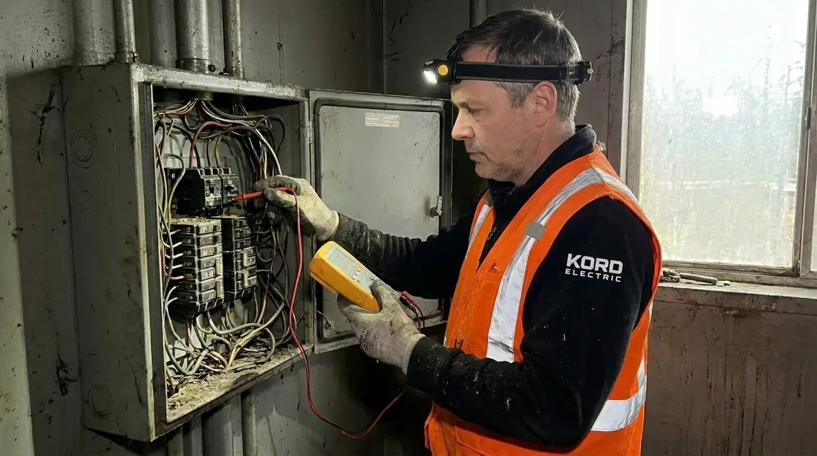 Technician inspecting commercial electrical panel for safety risks