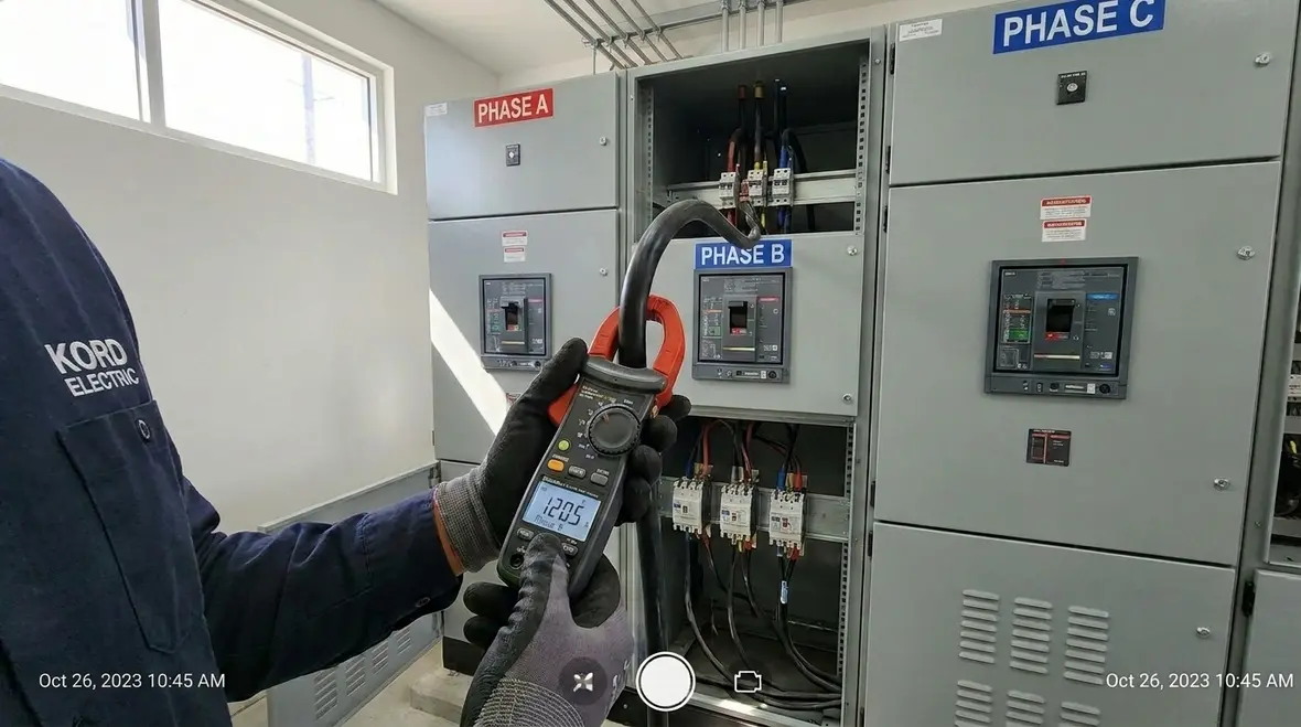 Technician inspecting a commercial electrical panel for load imbalance issues