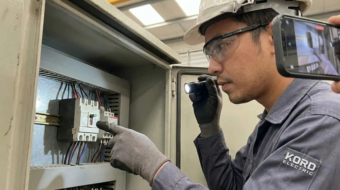 Industrial electrician measuring voltage and current during systematic troubleshooting