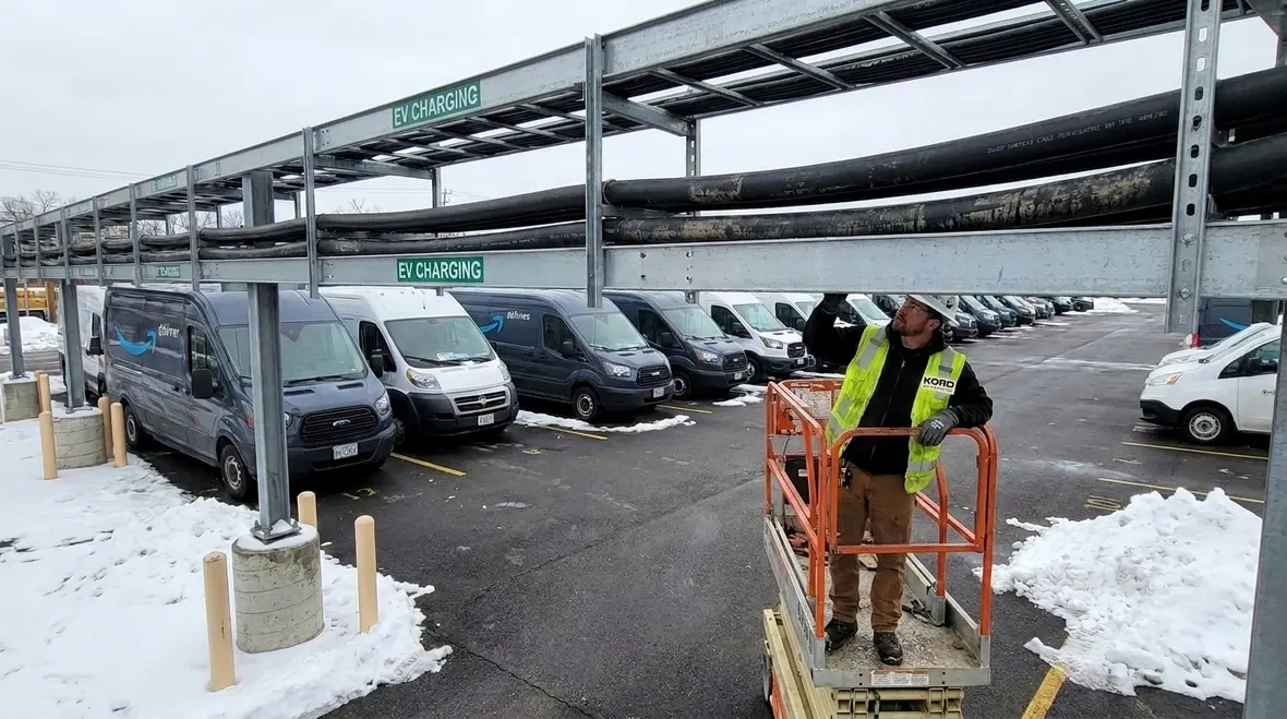Protected EV charging cable routing with conduit and overhead paths in a fleet yard