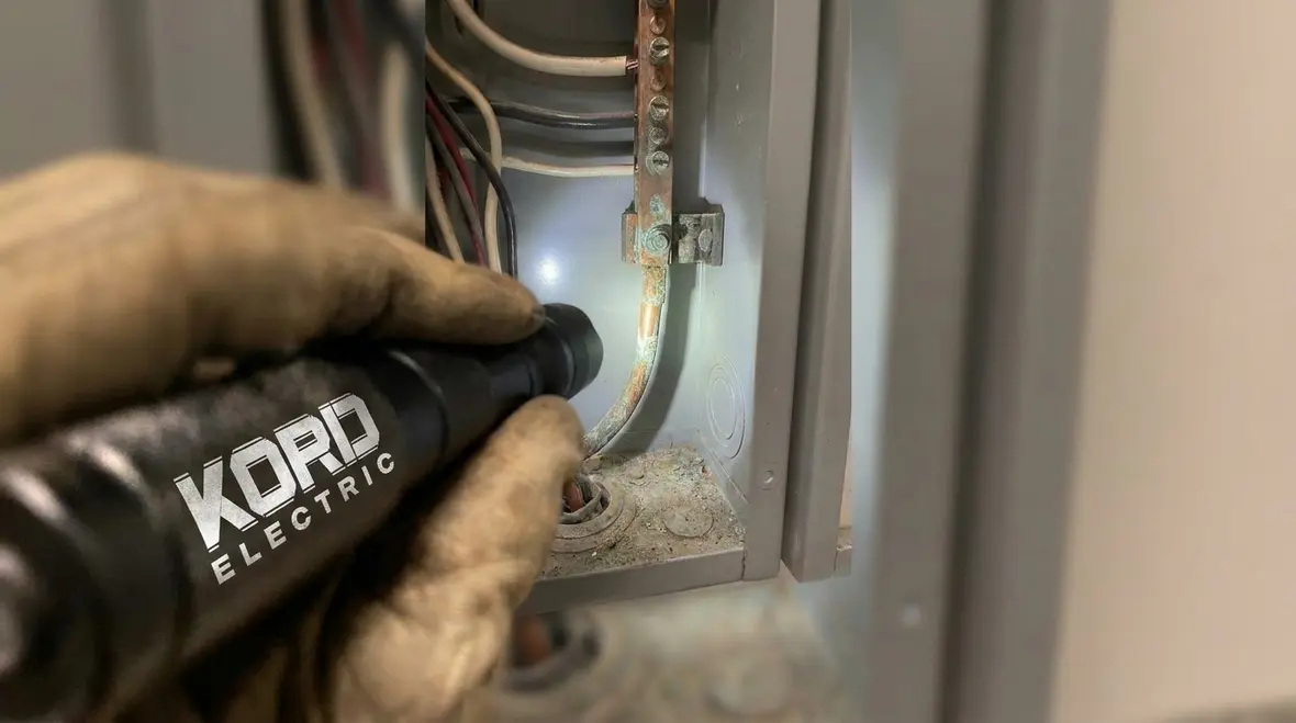 Technician inspecting commercial electrical grounding requirements california in a main service room