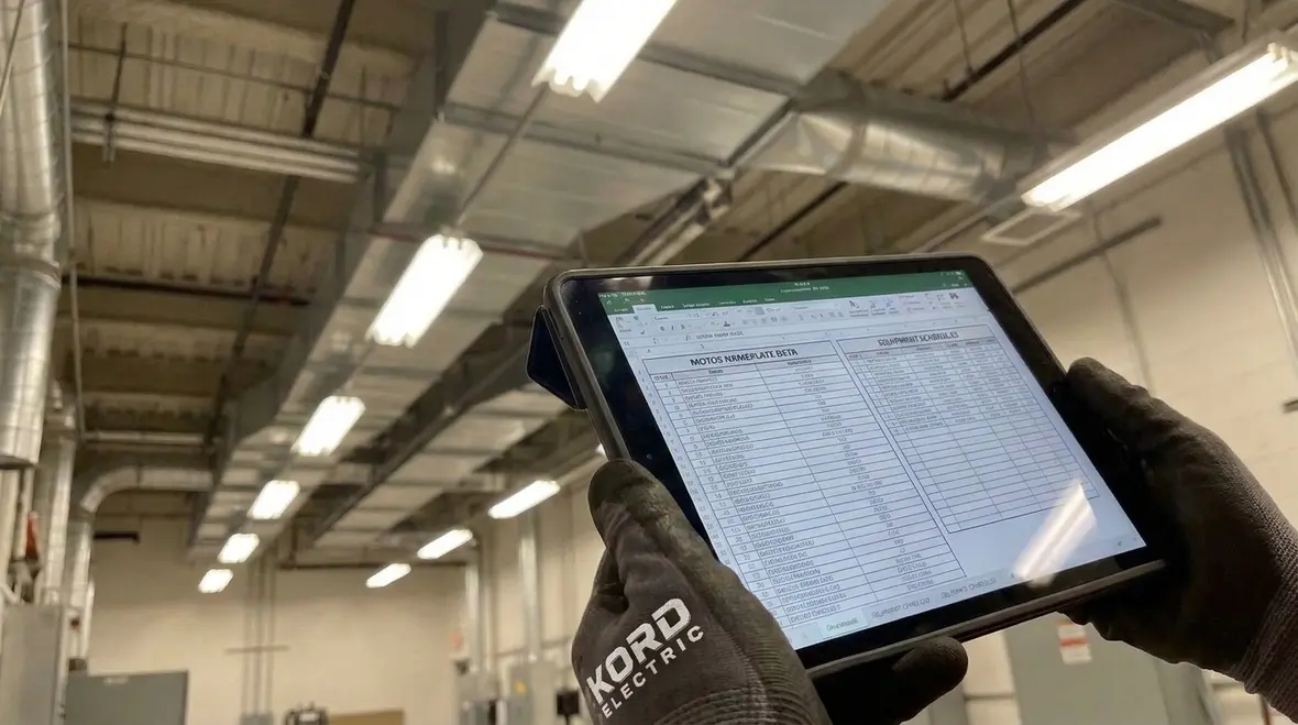 Engineer cross checking commercial electrical equipment lists in a mechanical room