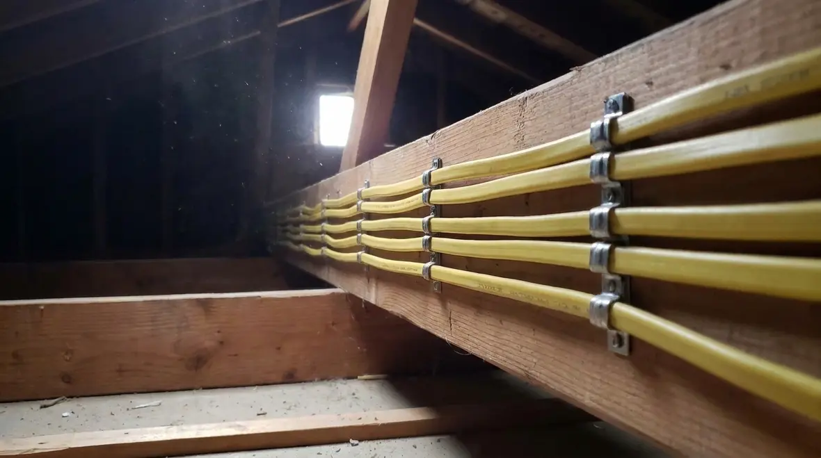 Properly secured NEC NM cable installation running through a commercial attic space