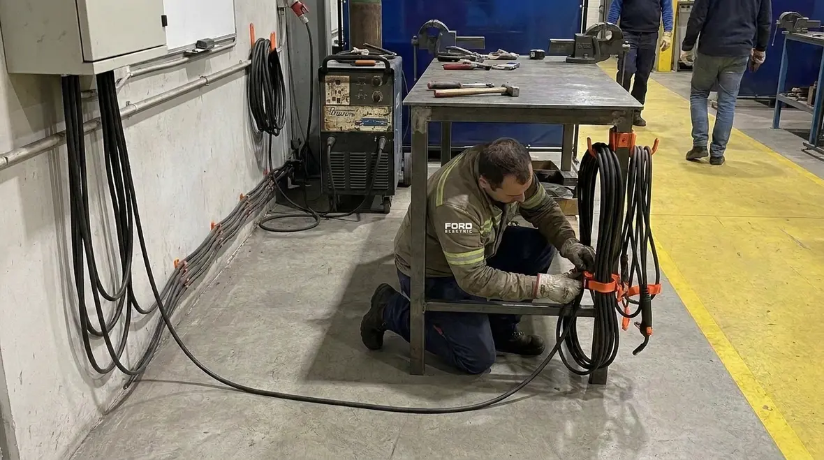 Technician inspecting NEC Section 630.41 welding secondary circuit conductors in a commercial facility