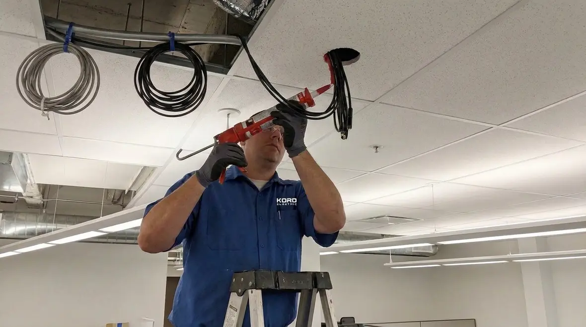 Technician installing a loudspeaker in a fire-rated ceiling following NEC Section 640.25