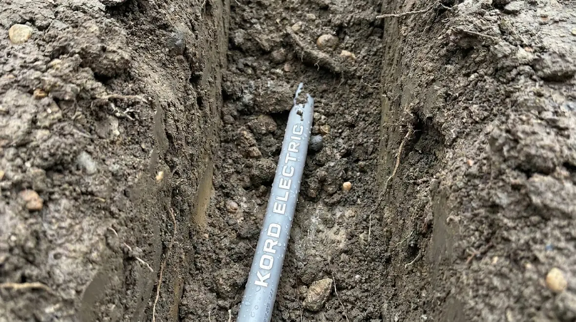 Technician reviewing NEC UF cable exposure to moisture in a commercial trench
