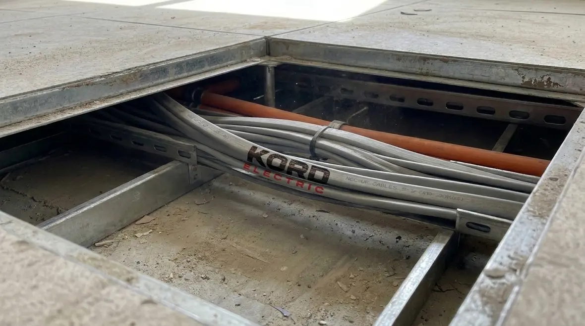 Electrician reviewing NEC UF cable placement under commercial floor coverings
