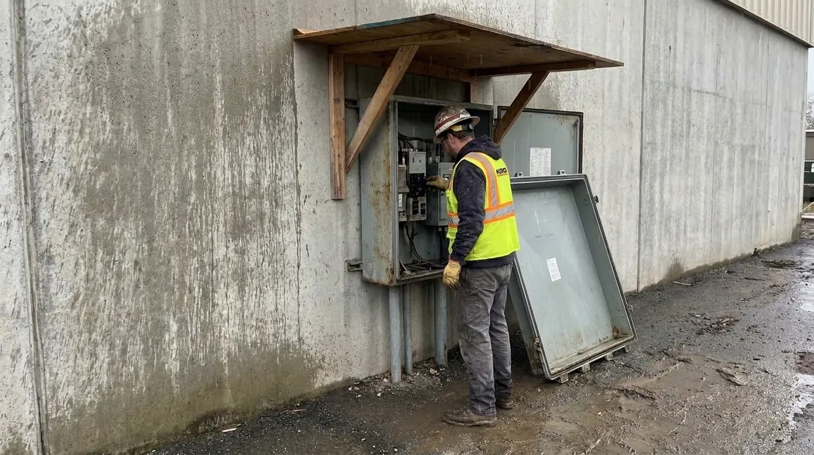 Electrical technician inspecting NEC box covers canopies for NFPA 70 Section 314.25 compliance