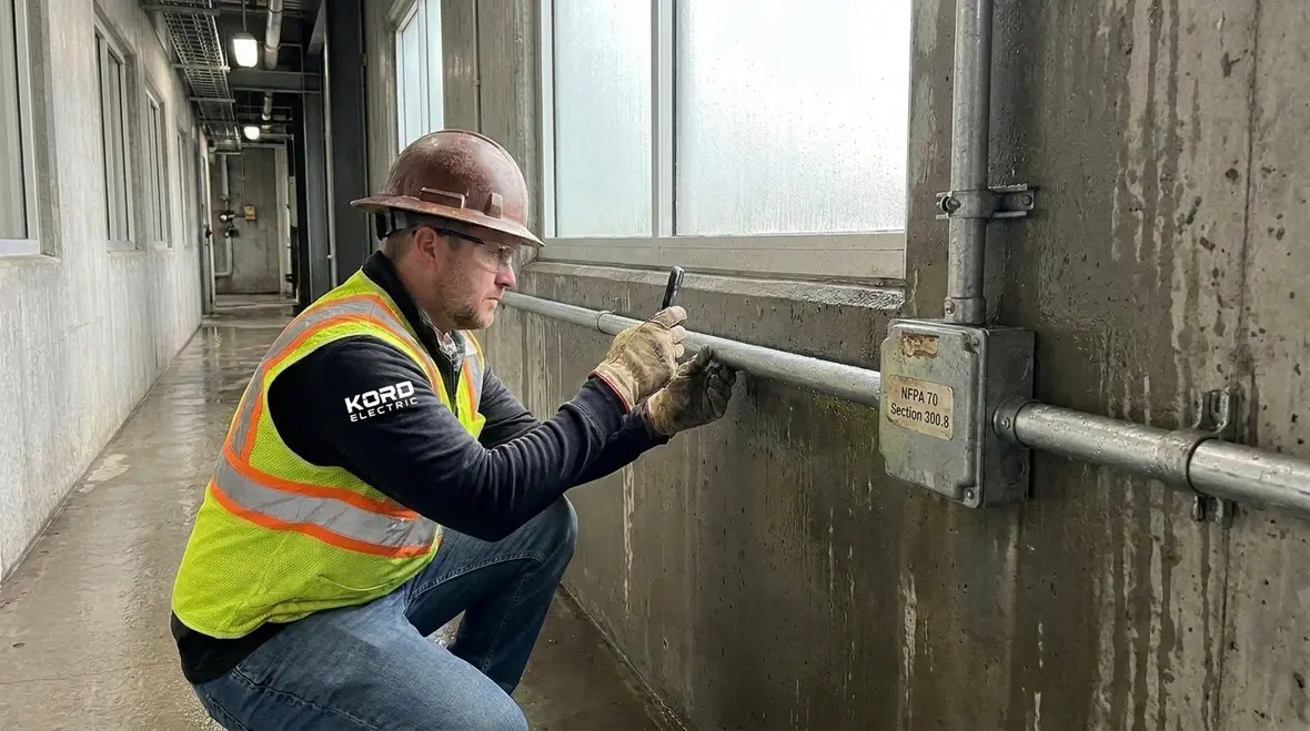 Electrician reviewing NEC corrosion protection wiring methods in a commercial facility