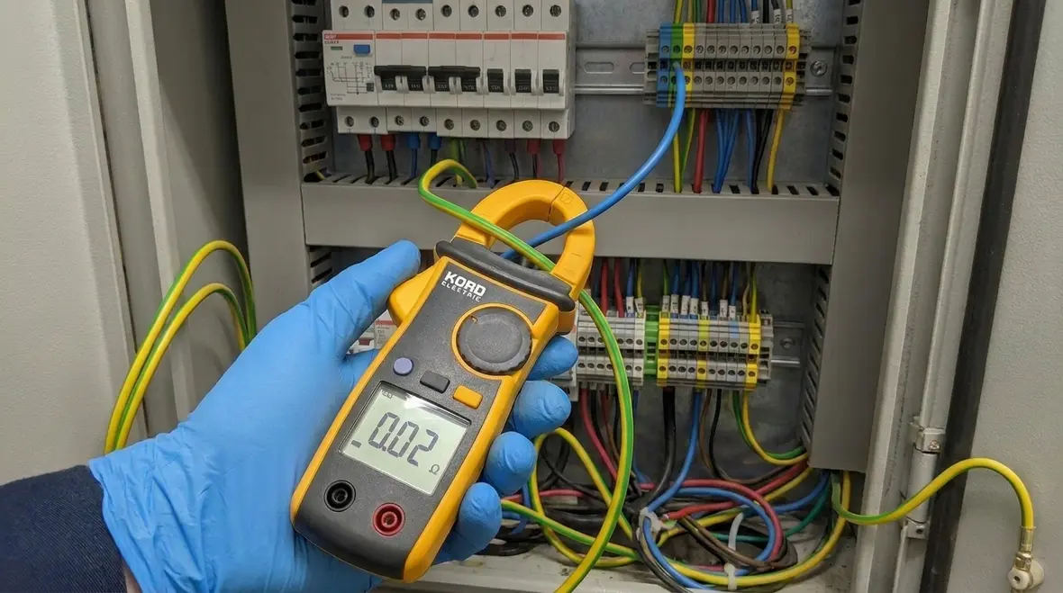 Technician reviewing NEC neutral equipment grounding banned 2 kV layout in a commercial panel