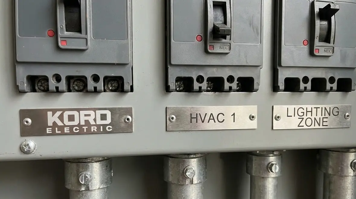 Technician reviewing NEC nontamperable circuit breakers inside a commercial electrical panel
