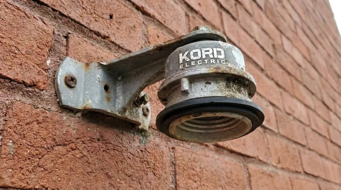 Technician inspecting commercial NEC-compliant outdoor lampholder installation