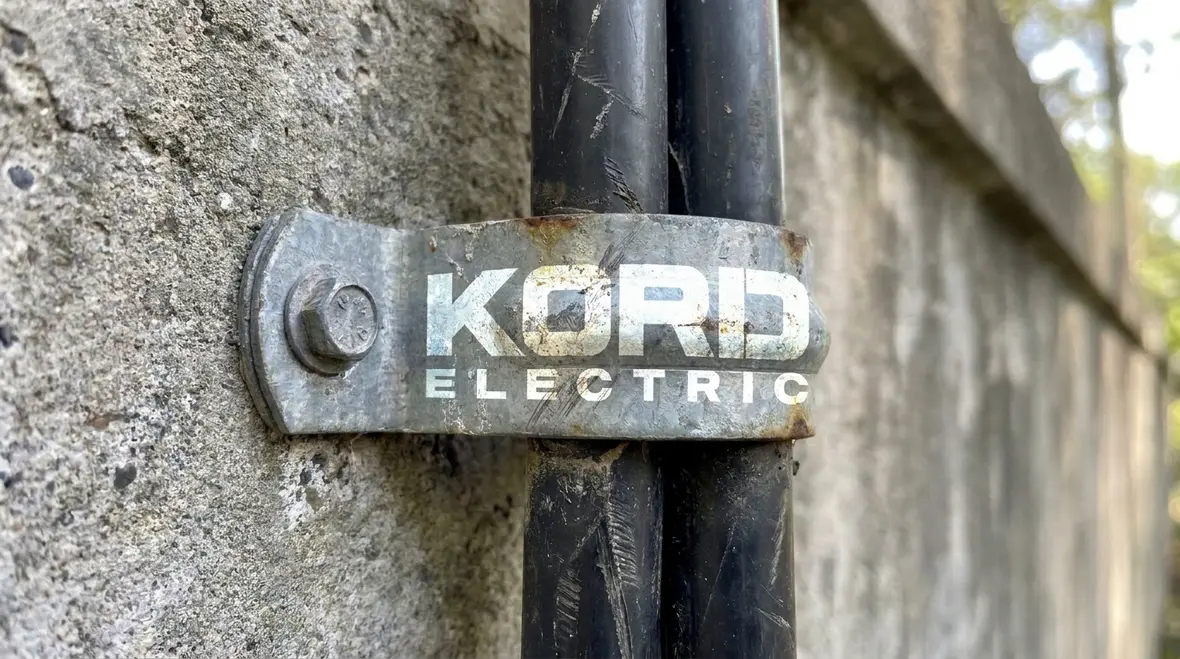 Kord Electric technician verifying NEC-compliant mounting supports on a service entrance