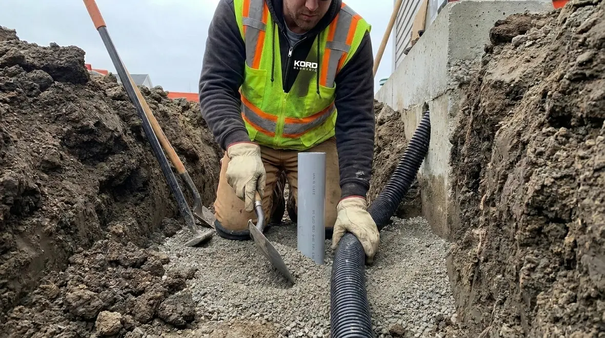 Technicians installing NEC underground service insulation in a commercial trench