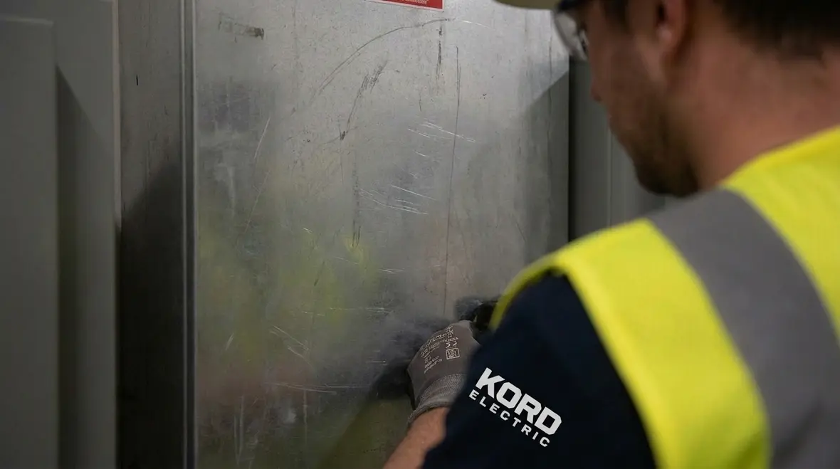 Technician verifying electrical room signage against NEC requirements