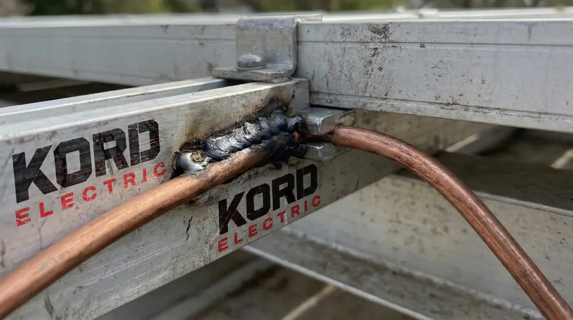 Close-up of bonded metal PV frames and grounding hardware on an industrial solar array